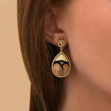 Boucles d'oreilles clips dorées en marqueterie de plumes naturelles beiges et cuir d'agneau doré, cristaux, collection Fujita – photo portée